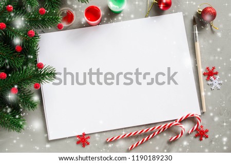 Christmas mock up for greeting card or letter to Santa. Xmas background with empty white paper, paints and fir branches. Copy space, snow effect. View from above. Royalty-Free Stock Photo #1190189230