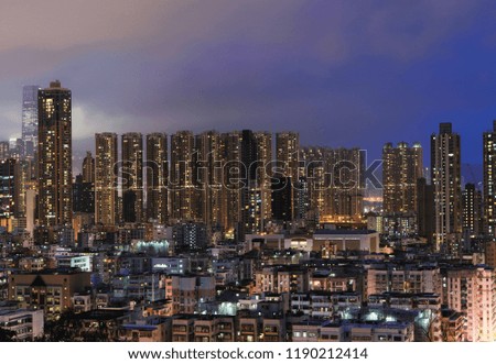 Aerial view of Hong Kong apartments and mountain in cityscape background. Residential district in smart city in Asia. Buildings at night.