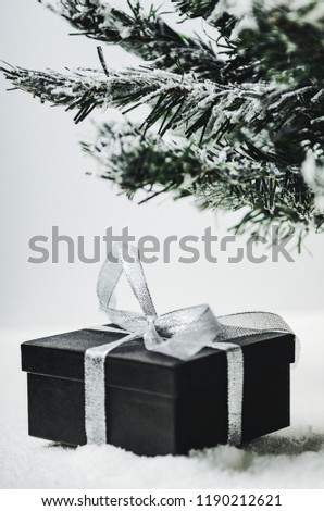 Gift box with a bow of silver ribbon under the spruce. New Year's surprise from Santa Claus.
