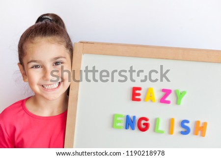 Language education concept.Learn English. Back to school Cute little child girl with colored letters on the blackboard. English language school. English for children.