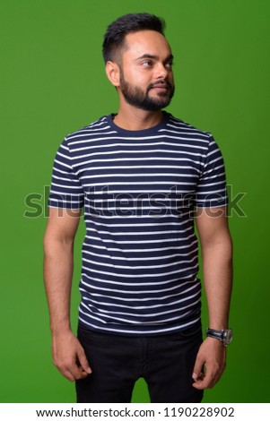 Young bearded Indian man against green background