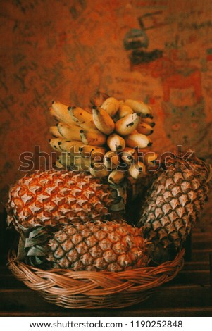 Banana and pineapple with orange light with strong shadow and grain.The banana and pineapple with grain ,strong shadow with soft focus.