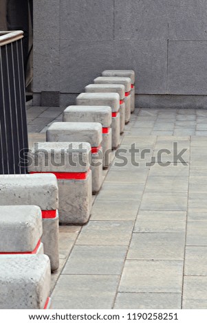 Road barriers made of concrete blocks with rounded corners and a red reflective strip