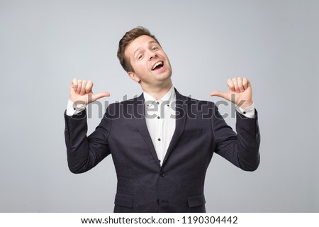Very proud man shows his fingers on himself standong isolated on lgray background. Handsome businessman is happy that he managed to conclude a bargain Royalty-Free Stock Photo #1190304442