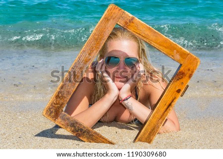 Pretty woman on beach with wooden picture frame