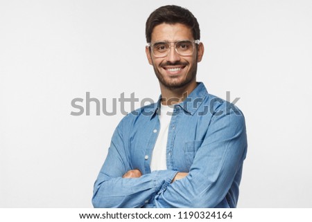 Portrait of smiling handsome business man in casual blue denim shirt standing with crossed arms, isolated on gray background