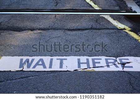 Close up view of Wait Here sign at railway crossing