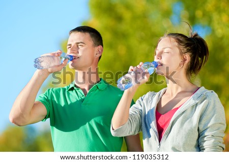 Man and woman drinking water from bottle after fitness sport exercise