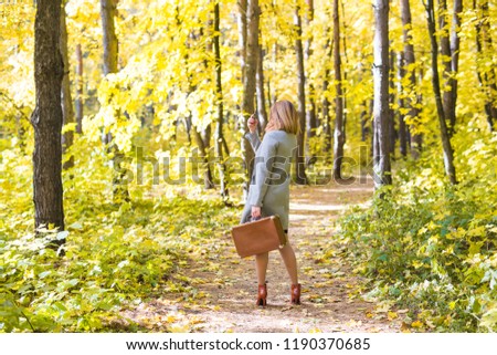Season, technology and people concept - beautiful young woman in autumn nature taking selfie with smartphone