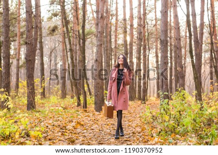 Fall, season and people concept - young woman walking in park at autumn