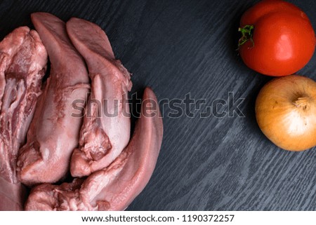 raw pork or beef tongues with vegetables tomatoe, onion on black wooden, gourment food conception, free space for text