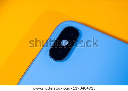 New dual camera as hero object on bright glamorous modern neon pop orange background - smartphone telephone with OLED display