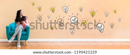Many light bulbs with young woman holding a tablet computer in a chair
