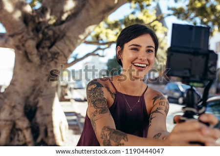Stylish young woman recording content for her daily vlog outdoors on city street. Woman taking video on camera for vlog. Royalty-Free Stock Photo #1190444047