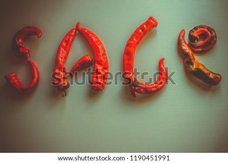 Red letters on a dark background. Hot offer, sale, Black Friday. The inscription is made of spicy chili peppers. Toning, vignetting, copy space. View from above.