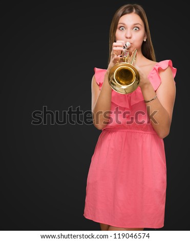 Young Woman Blowing Trumpet against a black background