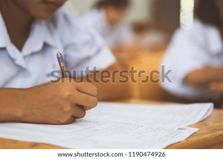 School students  taking exam writing answer in classroom with stress