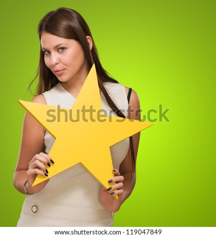 Portrait Of Young Woman Holding Yellow Star against a green background