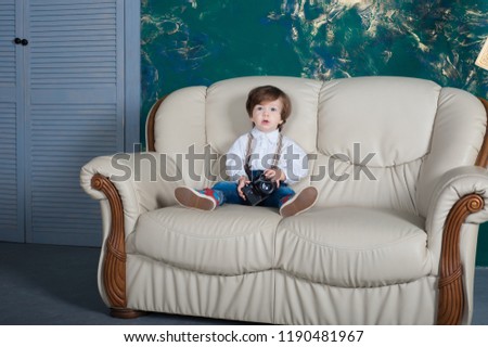 Cute little boy sitting on sofa, indoors