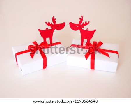 Two red deer standing on two christmas gifts with red ribbons and white background.