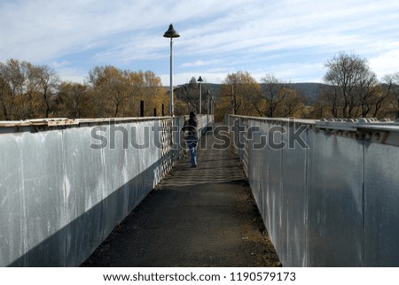 Young woman walking over a railway bridge