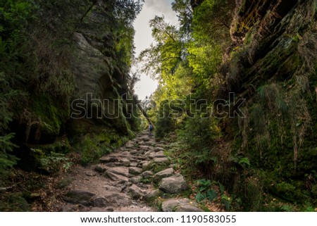 Woman with a backpack walking on a path between two mountains
