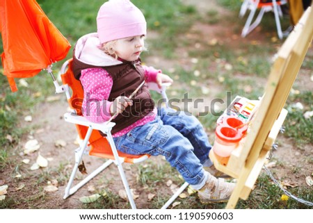 little girl draws  on the easel. the child paints  