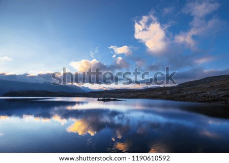 Reflection on a lake in the mountains of Switzerland. Mountain lake in the alps. Morning mood with a cloudy sky. Sunrise in the landscape.