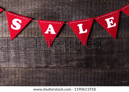 Red triangle flags hanging over wooden background with sign sale, closeup and nobody