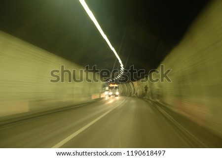 Trucks coming around bend in Tunnel. Black ceiling and white walls.  Car point view image during driving through tunnel.