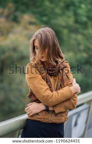 A very beautiful girl is standing on an iron bridge and is posing on the camera.