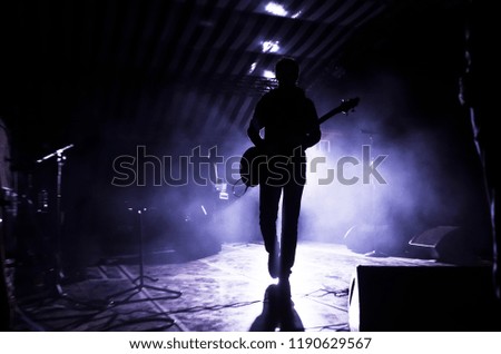 silhouette of a musician, a singer with a guitar on stage in the beams of searchlights. concept of music and rock festival