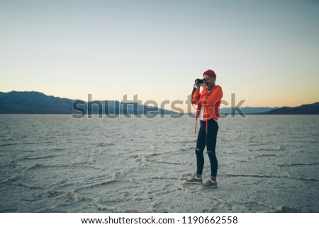 Tourist woman traveler making photo on camera exploring wild lands in Death Valley, professional female photographer taking image of evening sunset and landscape having trip in scenery Badwater basin