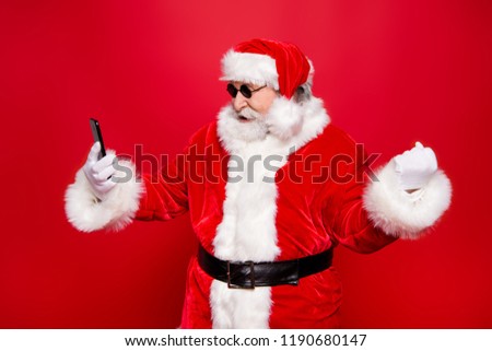 X mass wish eve noel. Profile side view aged mature grandfather stylish trendy Santa in headwear tradition costume white beard look gadget device hold fists hand isolated on red background