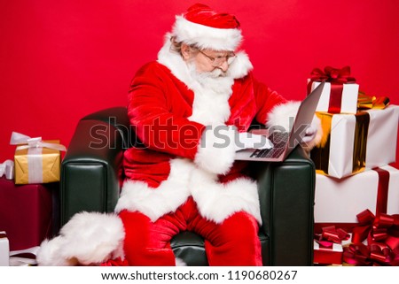 Christmastime winter december eve noel. Profile side view aged focused concentrated reader grandfather Santa white beard sit in armchair look at screen wish send receive email isolated red background