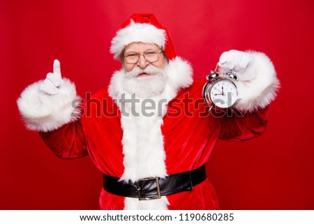 Holly jolly x mas coming! Punctual free time concept. Stylish mature aged Saint Nicholas indicate show point finger forefinger in gloves up hold clock isolated on shine red background