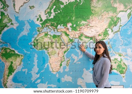Woman touching world map looking at camera, geography Royalty-Free Stock Photo #1190709979