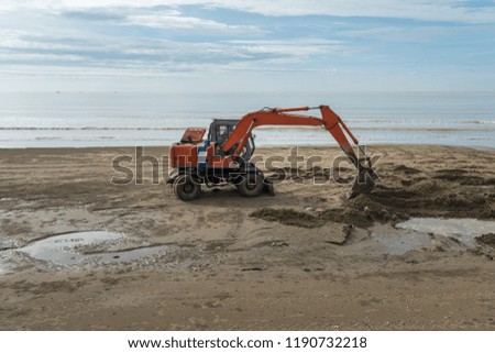Excavator working on the beach to smooth the sand before summer season beginning Royalty-Free Stock Photo #1190732218