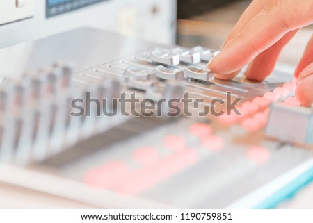 sound engineer fingers adjusting audio level on digital mixing console fader, recording concept