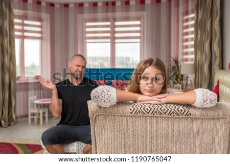 family relationships, family conflict father and adult daughter. The family sits in the room on the sofa, arguing and looking displeased.