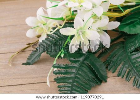 White artificial flowers on wooden background, closeup picture.