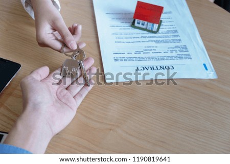 estate agent giving house keys to owner and sign agreement in office