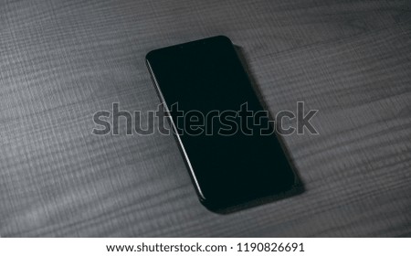 Black mobile smartphone on wooden table mockup 