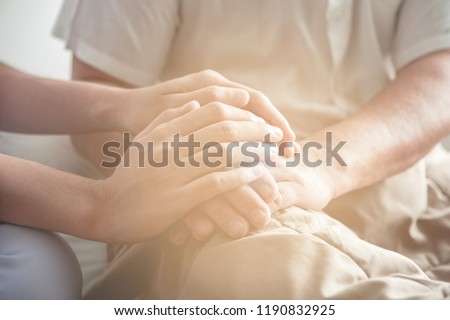 Comforting hand. Young nurse holding old man's hand. Senior care, care taker and senior retirement home service concept. Close up shot. Royalty-Free Stock Photo #1190832925