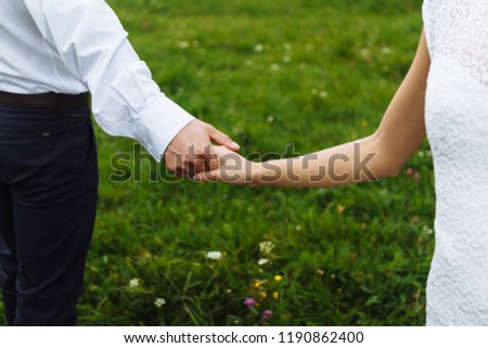 Wedding couple, bride and groom, new married holding hands, togetherness concept, green grass background