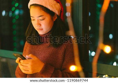 An Asian young woman sends messages of blessing to her mobile phone and friends on Christmas Eve.
