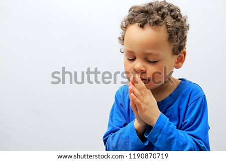 little boy praying to God stock image with hands held together with closed eyes with people stock photography stock photo Royalty-Free Stock Photo #1190870719