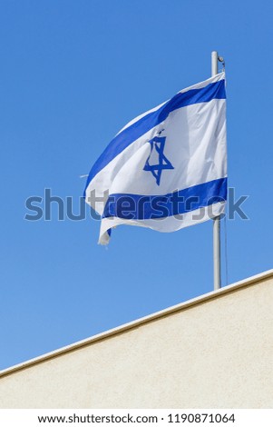 Flag of Israel over white wall at blye sky background