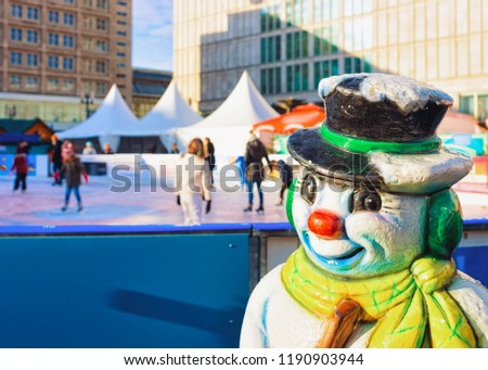 Snowman figurine at Skating rink on Christmas Market on Alexanderplatz in Winter Berlin, Germany. Advent Fair Decoration and Stalls with Crafts Items on the Bazaar.