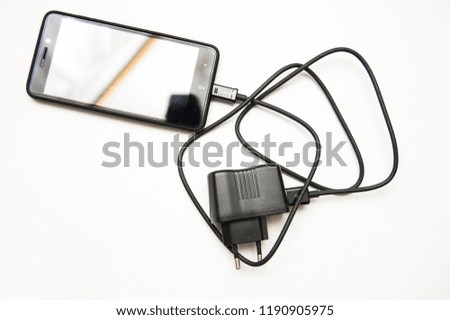Black smartphone with a comfortable charger on a white background. Copy space